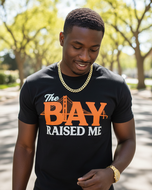 Man wearing a black t-shirt with 'The Bay Raised Me' design outdoors.