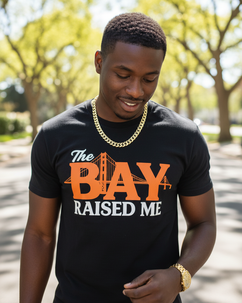 Man wearing a black t-shirt with 'The Bay Raised Me' design outdoors.